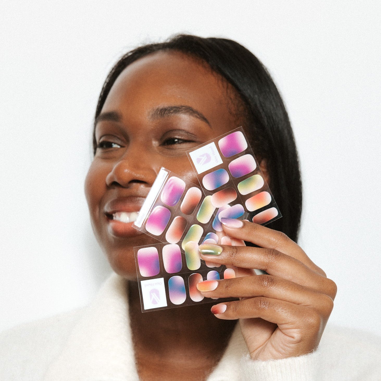 Every Mood Maniac Nails multi colors faded nail art on hand with woman smiling holding sheet