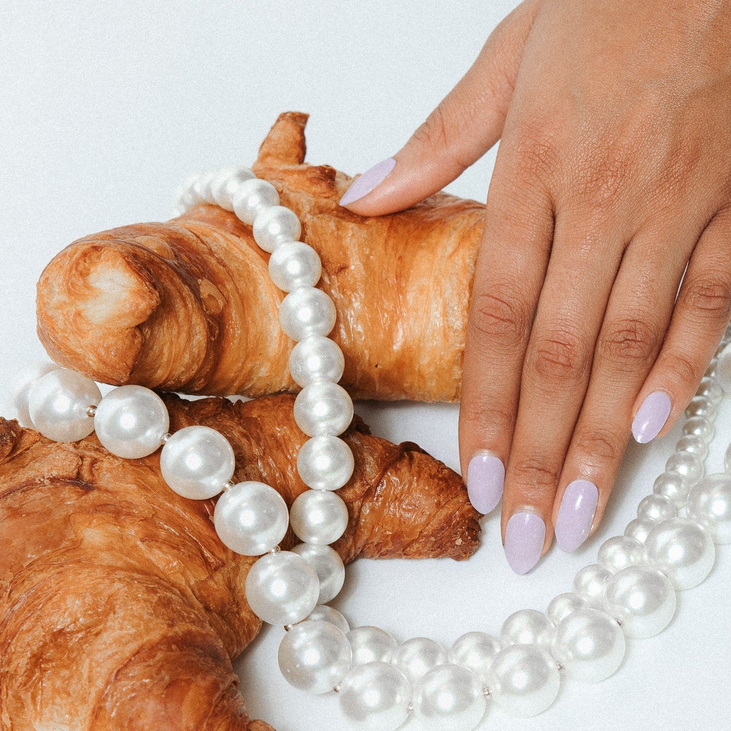 Giselle Gray Maniac Nails grey nail design sticker on hand with pearl necklace and croissant
