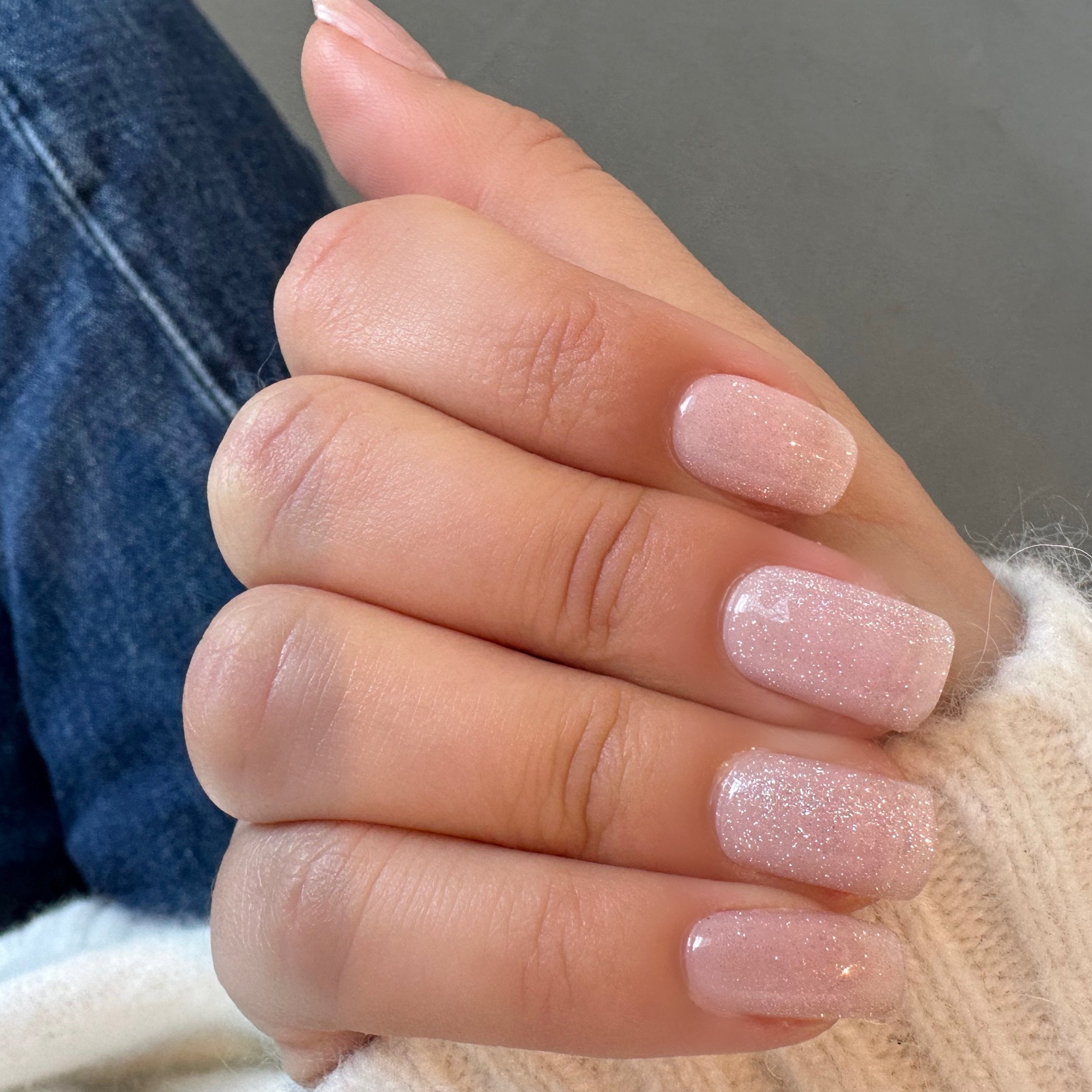 Hand met de Glossy Maniac gellak stickers en een witte trui