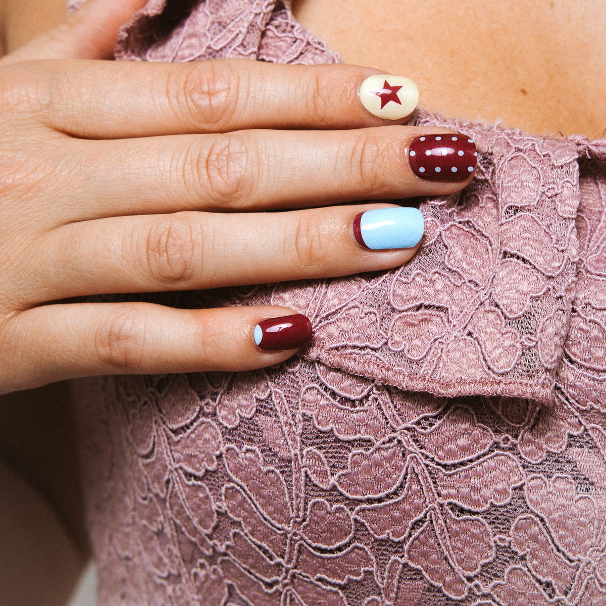 Close-up of All In nail art stickers by Maniac Nails, bordeaux, cream and baby blue nails with stars
