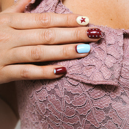 Close-up of All In nail art stickers by Maniac Nails, bordeaux, cream and baby blue nails with stars
