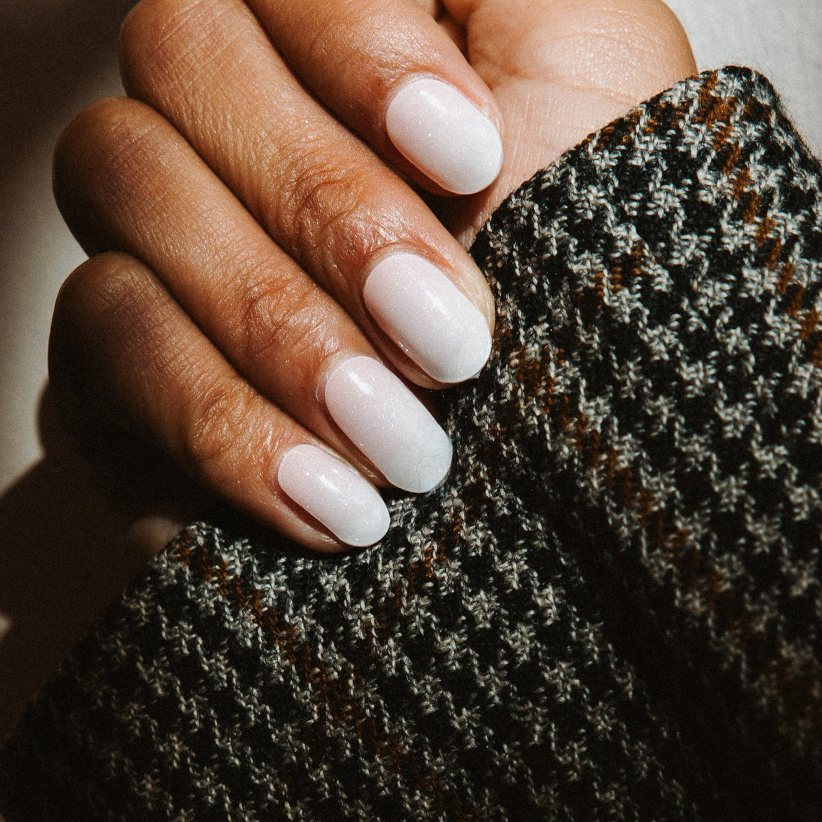 Hand with Babyboom Glitter gel nail stickers by Maniac Nails, soft white nails with a subtle shimmer
