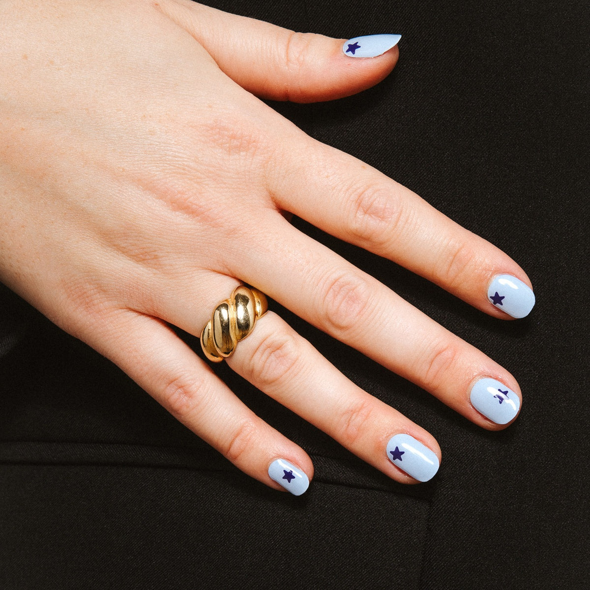 Close-up of Blue Wish gel nail stickers by Maniac Nails, soft blue manicure with navy stars