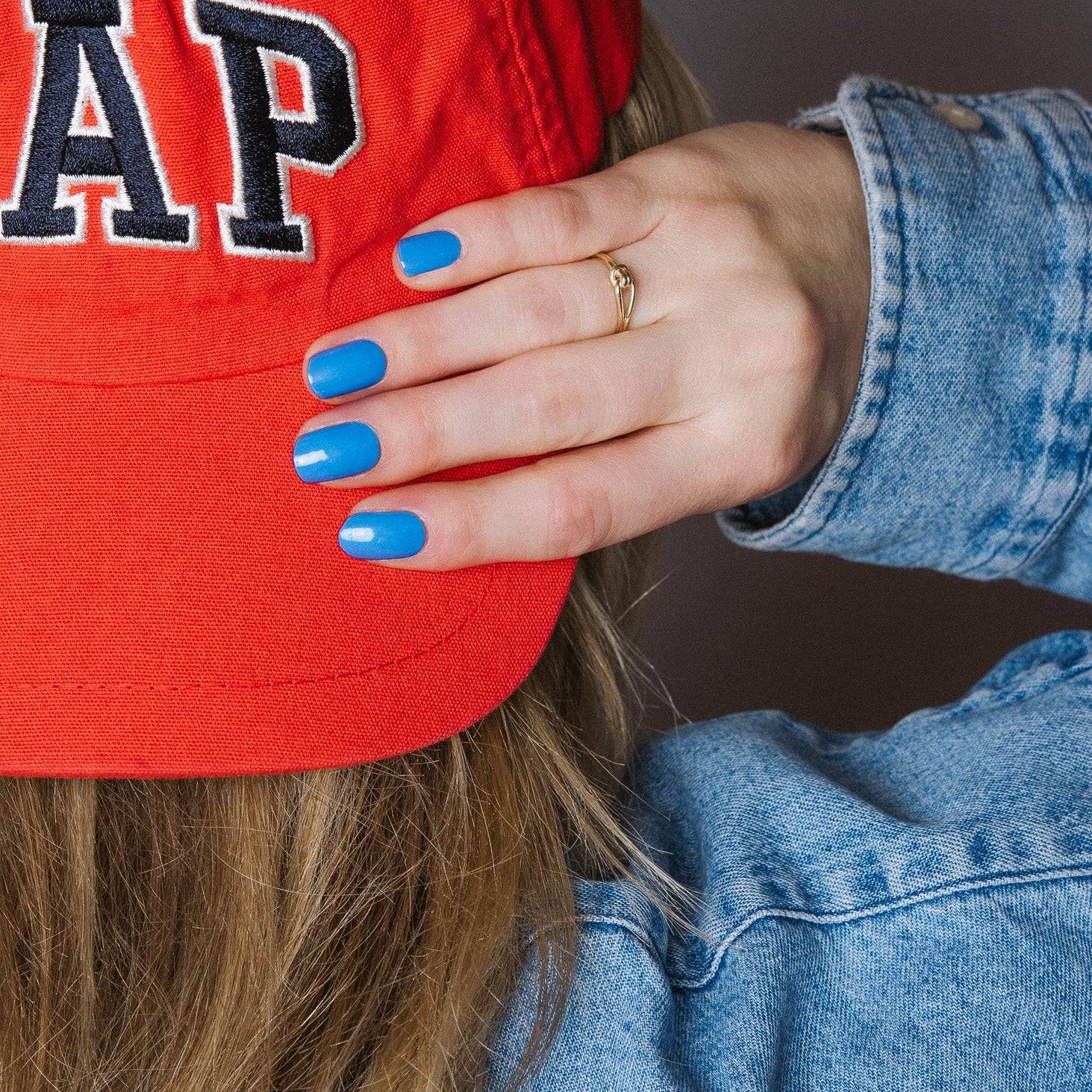 Bobby Blue Maniac Nails bright blue gel stickers on hand with red cap and denim jacket