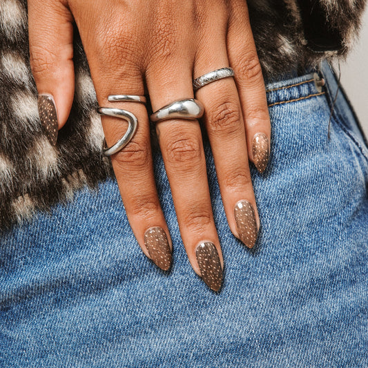 Hands with Deer Me gel nail stickers by Maniac Nails on denim, warm brown speckled nails