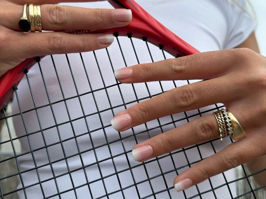 Handen met Timeless French Maniac manicure op tennisracket