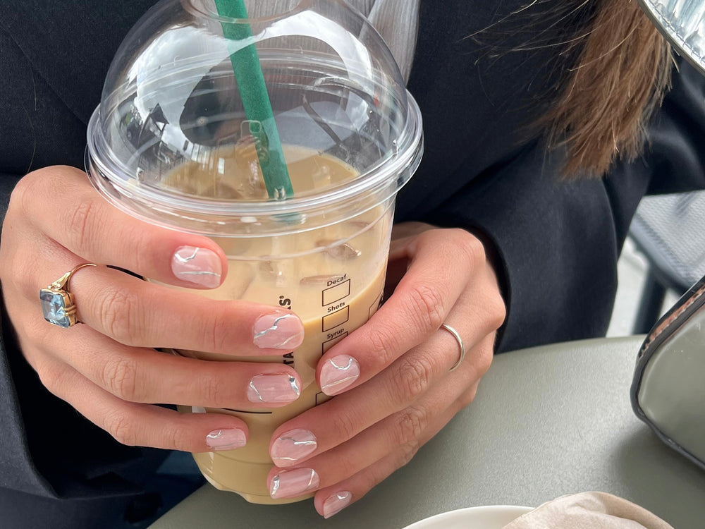 Influencers Nina and Jellina holding a coffee with a Maniac gel manicure with silver nail art lines Silverlined Bliss Nina & Jelina maniac Nails Gellak Sticker Silver Nail Art Manicure starbucks