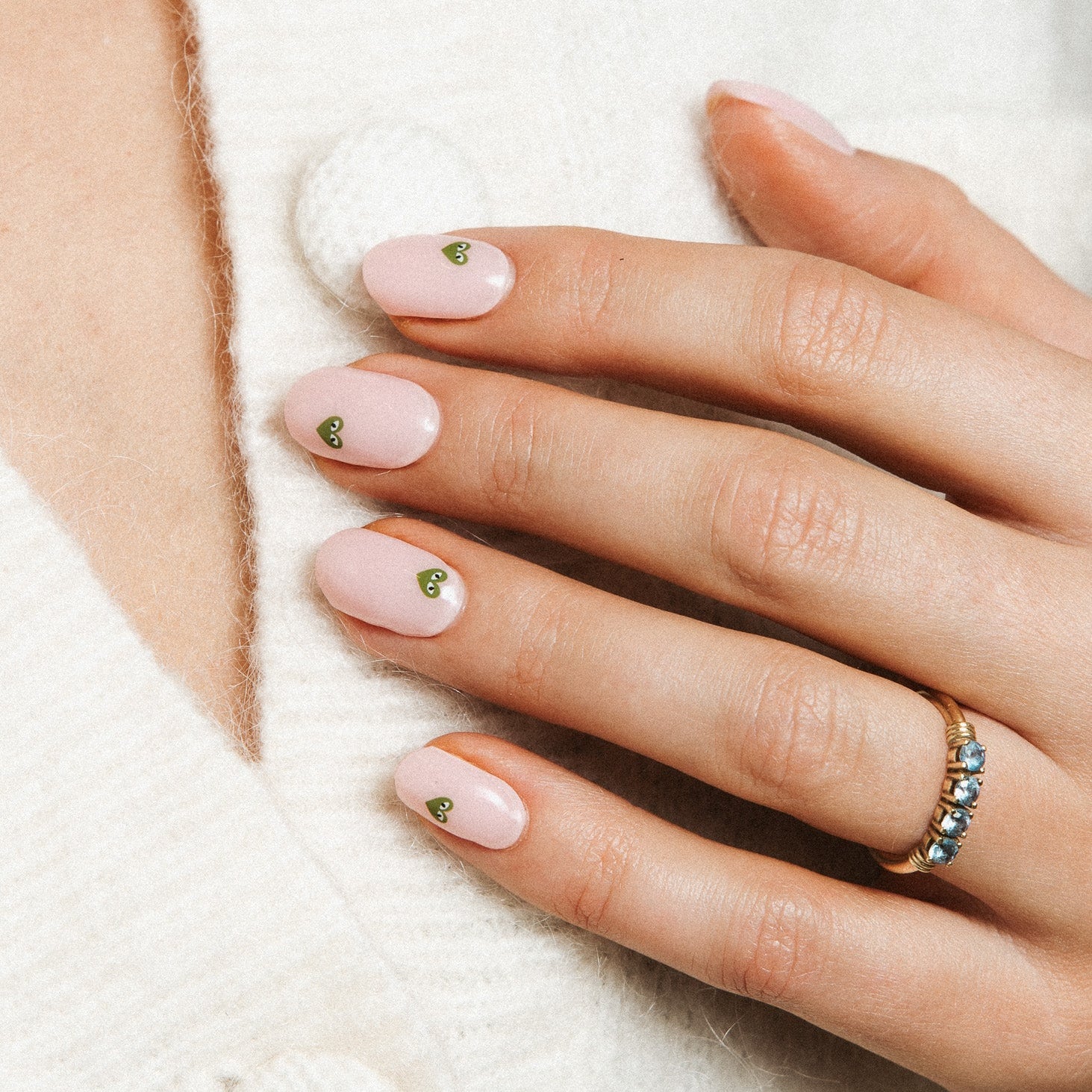 Minimal Crush Maniac Nails Light pink nail with green heart with eyes on hand white sweater 