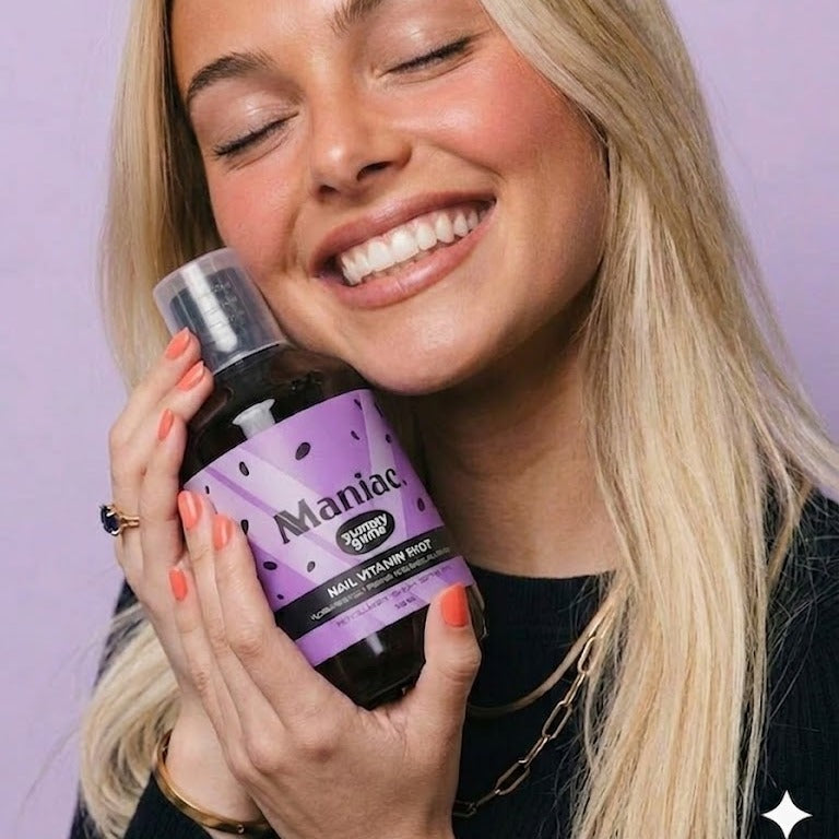 Lifestyle: woman holding the Maniac Nails Nail Vitamin Shot bottle. Liquid nail vitamins for daily use.