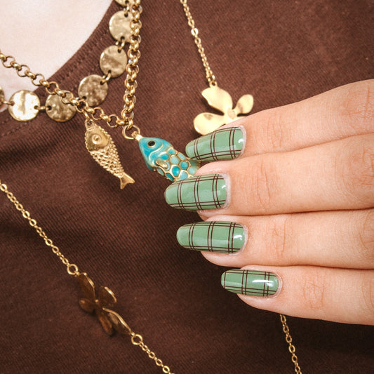 Hand with Old Money gel nail stickers by Maniac Nails, sage green nails with a bordeaux check print