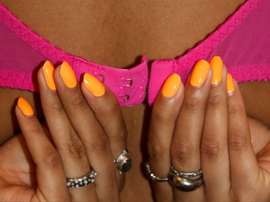 Hands unfasten bra with Oprah Orange Maniac Gel stickers