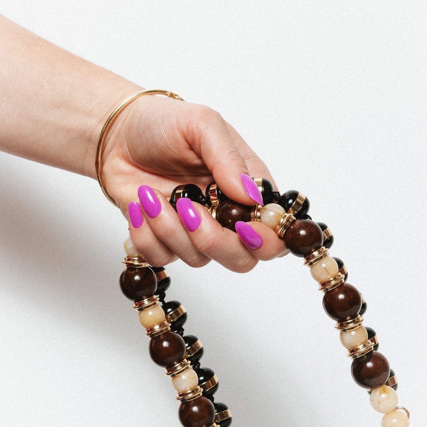 Pukka Purple Maniac Nails Bright purple nail design sticker on hand with brown and white chain 