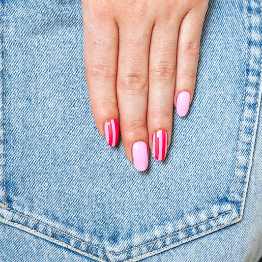 Hands with Suzy's Candy gel nail stickers by Maniac Nails on denim, pink nails with red stripes