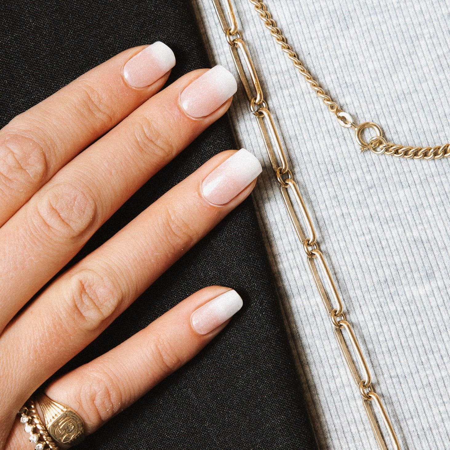 Hand with Timeless French Glitter gel nail stickers by Maniac Nails, white french tips with a soft shimmer