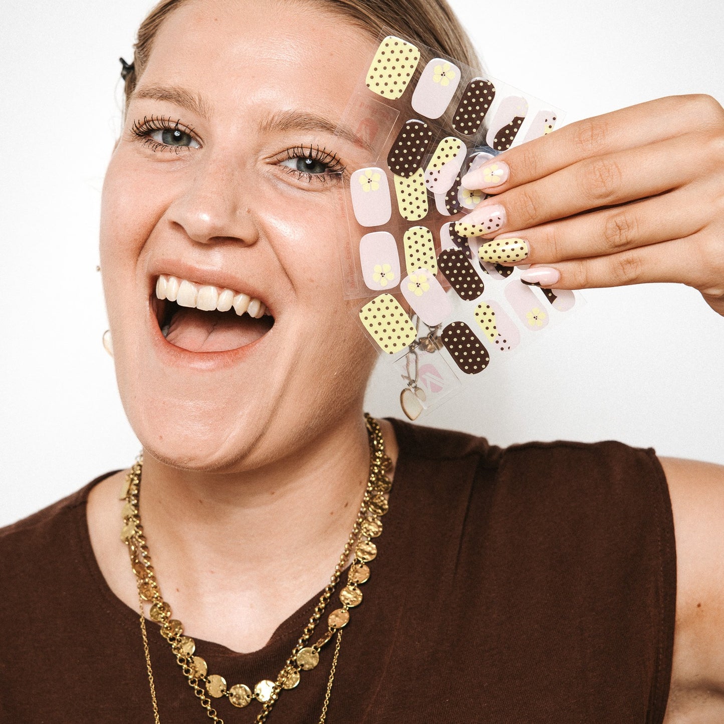 Model holding Toast and Honey gel nail sticker sheets by Maniac Nails