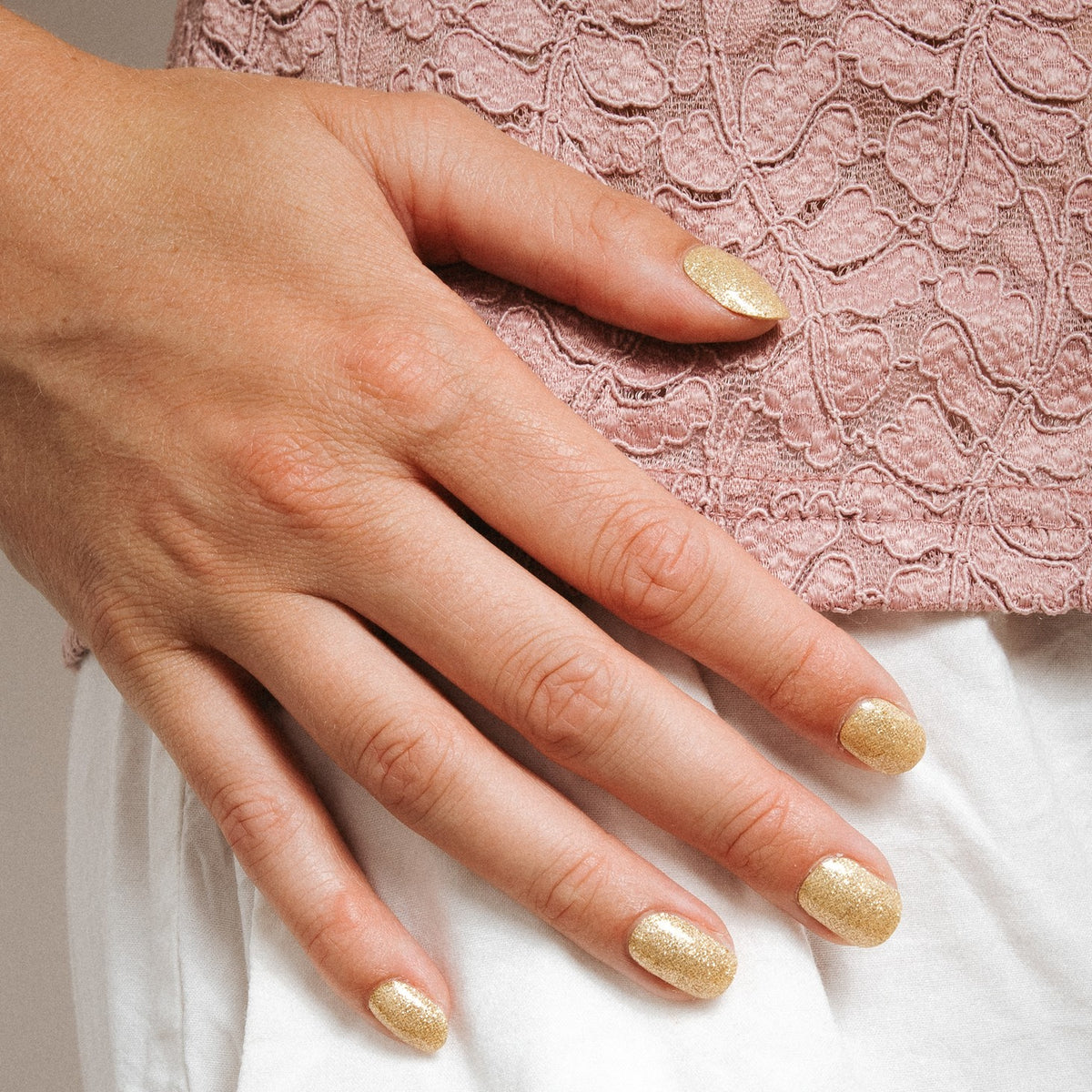 Close-up of Unstoppable gel nail stickers by Maniac Nails, sparkling champagne gold nails