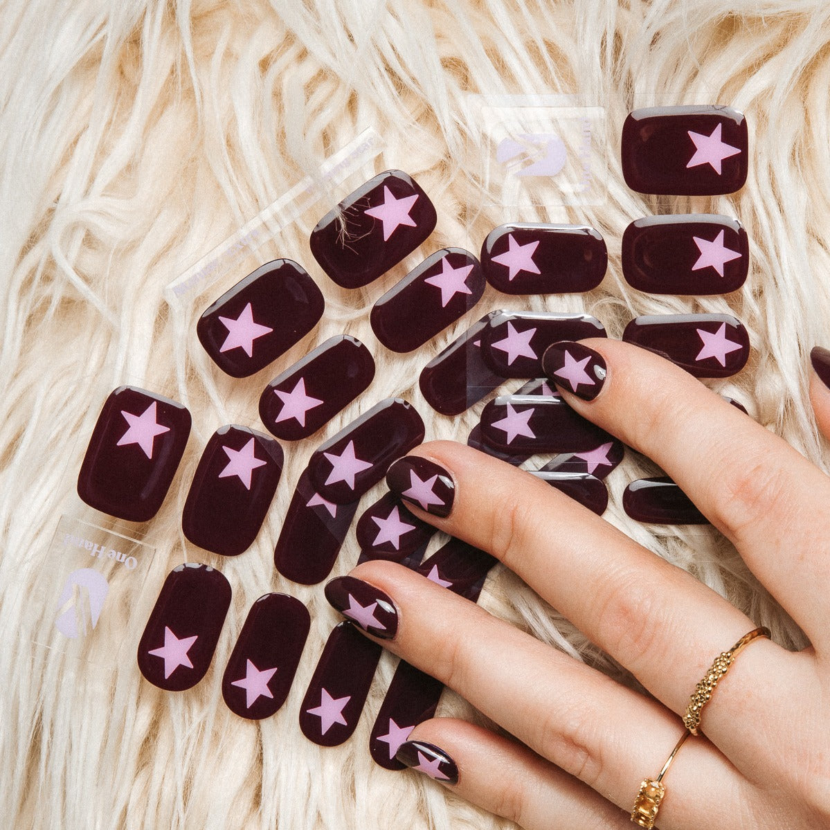 Hand holding Wishing Star gel nail sticker sheets by Maniac Nails on faux fur