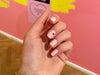 wit roze nagel met hartje aan de zijkant maniac nails voor een roze gele muur
