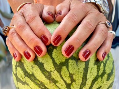 Bordeaux Red Maniac gellak stickers op handen die een meloen vasthouden
